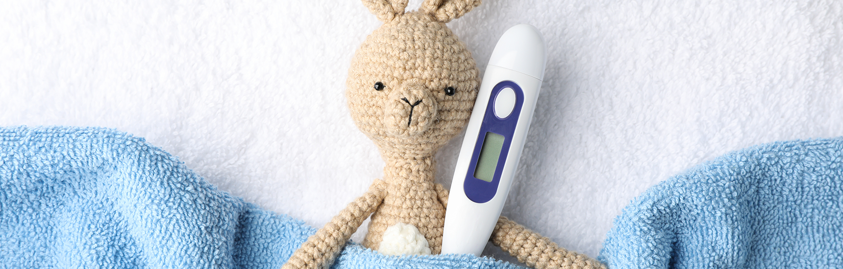 Thermometer und gehäkelter Hase als Symbol für Kindergesundheit